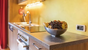 Une cuisine avec un saladier de fruits sur le comptoir, une cuisinière et un évier.