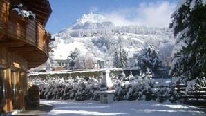 Une montagne enneigée, avec un bâtiment en bois au premier plan.