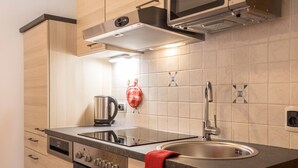 A modern kitchen with stainless steel appliances, a built-in oven, a sink, and a red towel hanging on the countertop. - Pet-friendly Apartment "Villa Anita Pares" with Mountain View, Sauna, Wi-Fi, Terrace & Balcony (St.Vigil)