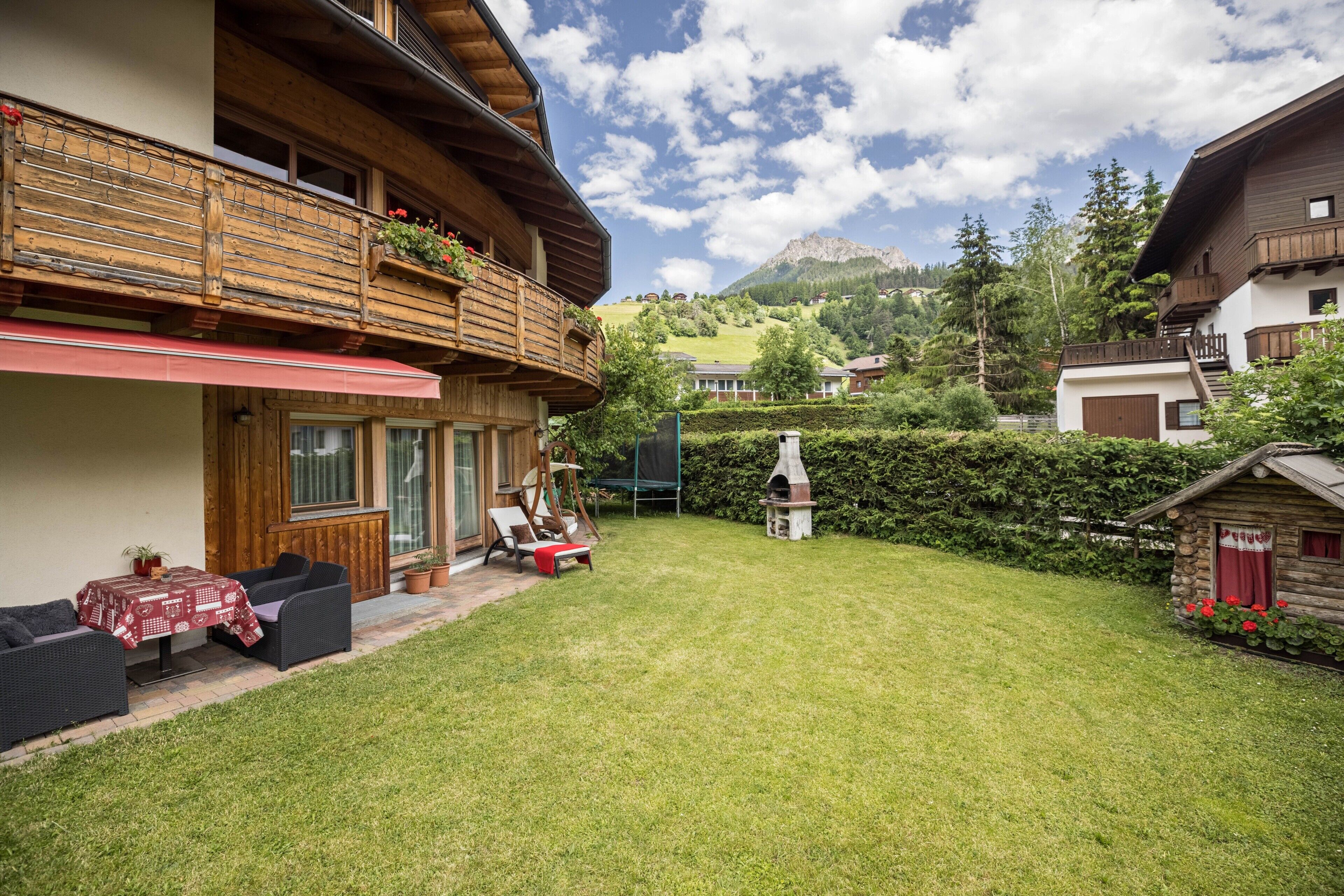 A chalet with a patio, outdoor seating, and a view of the mountains.