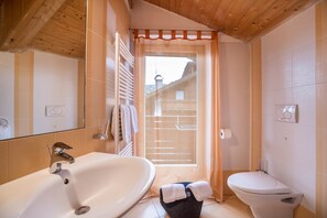 Ein Badezimmer mit Badewanne, Toilette und einem Vorhangfenster.