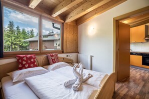 Ein Holzinnenraum mit einem Bett, einem Fenster mit Blick auf Bäume und einer Küchenzeile.