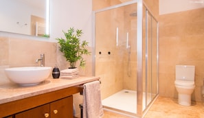 Un baño moderno con ducha de vidrio, lavabo blanco y retrete.