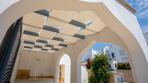 A covered outdoor area with a checkered ceiling, stone walls, and a view of a white building with a spiral staircase. - Villetta Clara, holiday house close to the beach (Nardo)