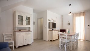 A spacious kitchen with white cabinetry, a dining table with chairs, and a blue sofa. - Villetta Clara, holiday house close to the beach (Nardo)