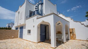 A white building with a spiral staircase, a balcony, and a stone-tiled patio with outdoor seating. - Villetta Clara, holiday house close to the beach (Nardo)