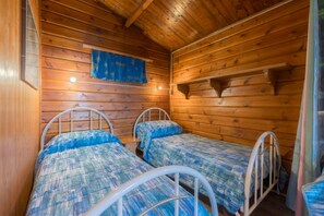 A cabin with two bunk beds, wooden walls, and a blue curtain. - APP.TI CHALET INES SECCIONE - CHALET SECCIONE 1 (Portoferraio)