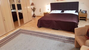 A bedroom with a large bed, a wardrobe, a nightstand, a lamp, and a vase with flowers. - Ferienhaus am Rheintor (Andernach)