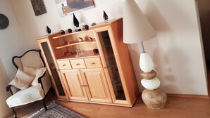 A room with a wooden cabinet, a chair, a lamp, and wall decorations. - Ferienhaus am Rheintor (Andernach)
