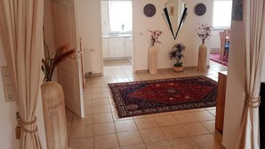 A hallway with a tiled floor, a red patterned rug, and a white door leading to a kitchen. - Ferienhaus am Rheintor (Andernach)