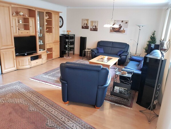A living room with a TV, sofas, a coffee table, and a cabinet.