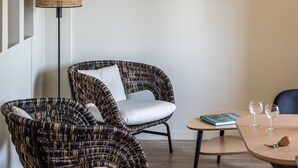 Un salón moderno con mobiliario de mimbre, una lámpara colgante y una escultura de peces en la pared.