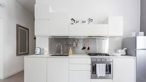 A modern kitchen with white cabinetry, a built-in oven, a gas stove, and a stainless steel sink.