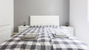 A bedroom with a checkered bedspread, two bedside tables with lamps, and a white headboard.