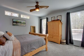 A bedroom with a bed, a wooden wardrobe, a ceiling fan, and a window with curtains. - 'The Hub' La Pine Vacation Rental - Dog Friendly! (La Pine)