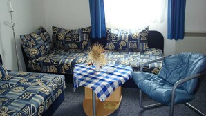 A room with a sofa set, a small table with a checkered tablecloth, and a chair. - Apartment for 2 people - Seahorse (Insel Hiddensee)