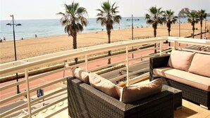A balcony with wicker furniture overlooking a beach. - Costa Azahar LEK (Peñiscola)