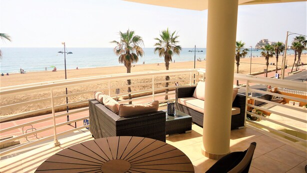 A balcony with a view of the beach, wicker furniture, and a round table. - Costa Azahar LEK (Peñiscola)