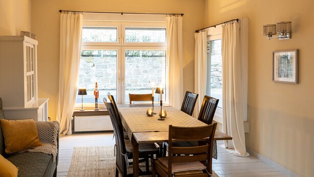 A dining room with a table set for six, a sofa, and a radiator.