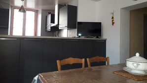 Una cocina moderna con armarios oscuros, un televisor de pantalla plana y una mesa de comedor con sillas.