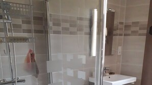 Un baño moderno con cabina de ducha de vidrio, un lavabo blanco y una alfombrilla de baño rosa.