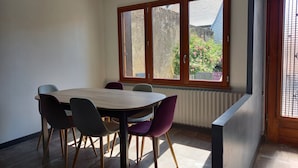 A dining area with a table and chairs, a window with a view of greenery, and a radiator under the window. - Maison 4/5 Personnes Avec Jardin Langeais Centre (Langeais)