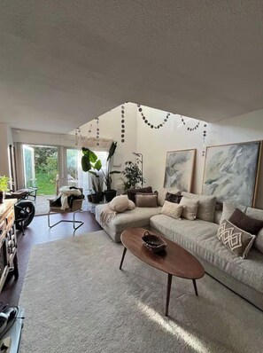 A modern living room with a sofa, coffee table, and large windows. - Garden-level duplex overlooking the ocean, Biarritz (Biarritz)