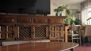 Un salon avec un téléviseur, un meuble en bois et une table à manger.