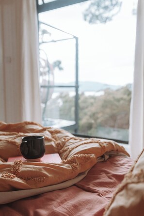A bed with a pink blanket and a black mug on a tray. - A cosy getaway you won't want to leave (Police Point)