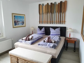 A bedroom with two beds, a headboard with wooden paddles, a framed picture on the wall, and a window with a view of a beach.