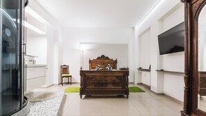 A room with a bed, a TV mounted on the wall, and a large mirror.