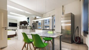 A modern kitchen with a dining table, chairs, and a refrigerator.