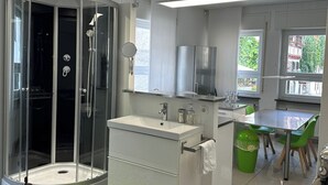 A modern bathroom with a glass-enclosed shower, a white sink, and a mirror.