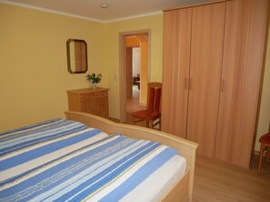 Une chambre à coucher avec un lit, une armoire en bois et une chaise.