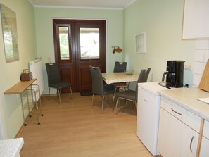 Une cuisine compacte comprenant une table à manger, des chaises, une machine à café et un réfrigérateur.