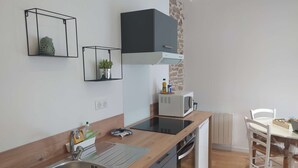 Uma cozinha moderna com micro-ondas embutido, pia de aço inoxidável e bancada de madeira.