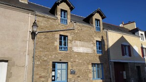 A stone building with multiple windows and a signboard. - Poterne du Tricot - Studio - 20m² - Maximum 2 Personnes (Guérande)