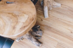A close-up of a wooden table with a natural grain pattern and a carved wooden footrest. - Spa Chalet Lodges by we rent (Zell am See)
