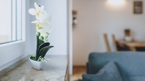 Una orquídea en maceta sobre un alféizar con vistas a un comedor y una lámpara fijada a la pared.