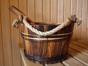A wooden bucket with a rope handle, placed on a wooden surface against a paneled wall. - Spa Chalet Lodges by we rent (Zell am See)