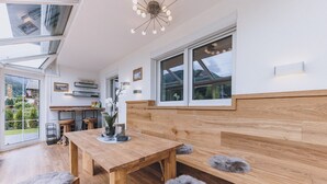 Un interior moderno con un banco de madera, una mesa de comedor y vistas amplias a través de grandes ventanales.