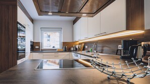 Una cocina moderna con una isla central, electrodomésticos de acero inoxidable y vistas a la ciudad a través de un amplio ventanal.