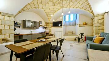Un espacio habitable compacto con un arco de piedra que da a una cocina y comedor.