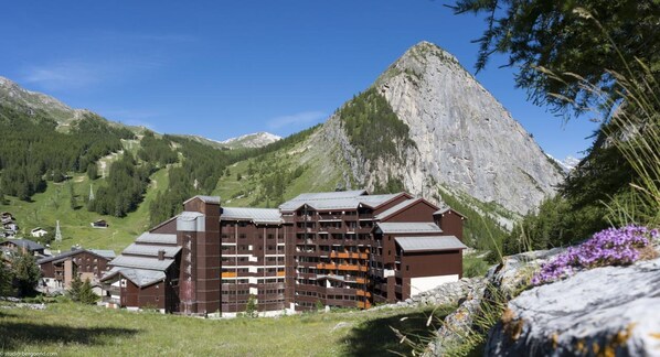 A multi-story hotel with a modern design, set against a mountainous backdrop. - Résidence La Daille - Val-d'Isère (Val-d'Isere)