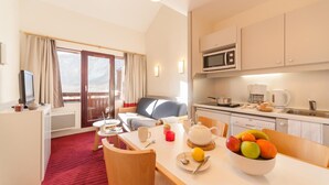 A hotel room with a dining area, kitchenette, and a balcony with curtains. - Résidence La Daille - Val-d'Isère (Val-d'Isere)
