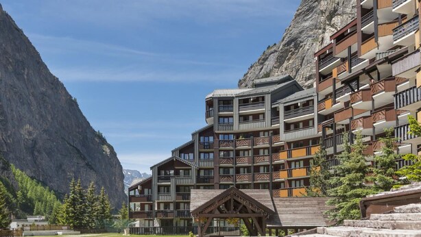 A multi-story hotel with balconies, set against a mountainous backdrop. - Résidence La Daille - Val-d'Isère (Val-d'Isere)