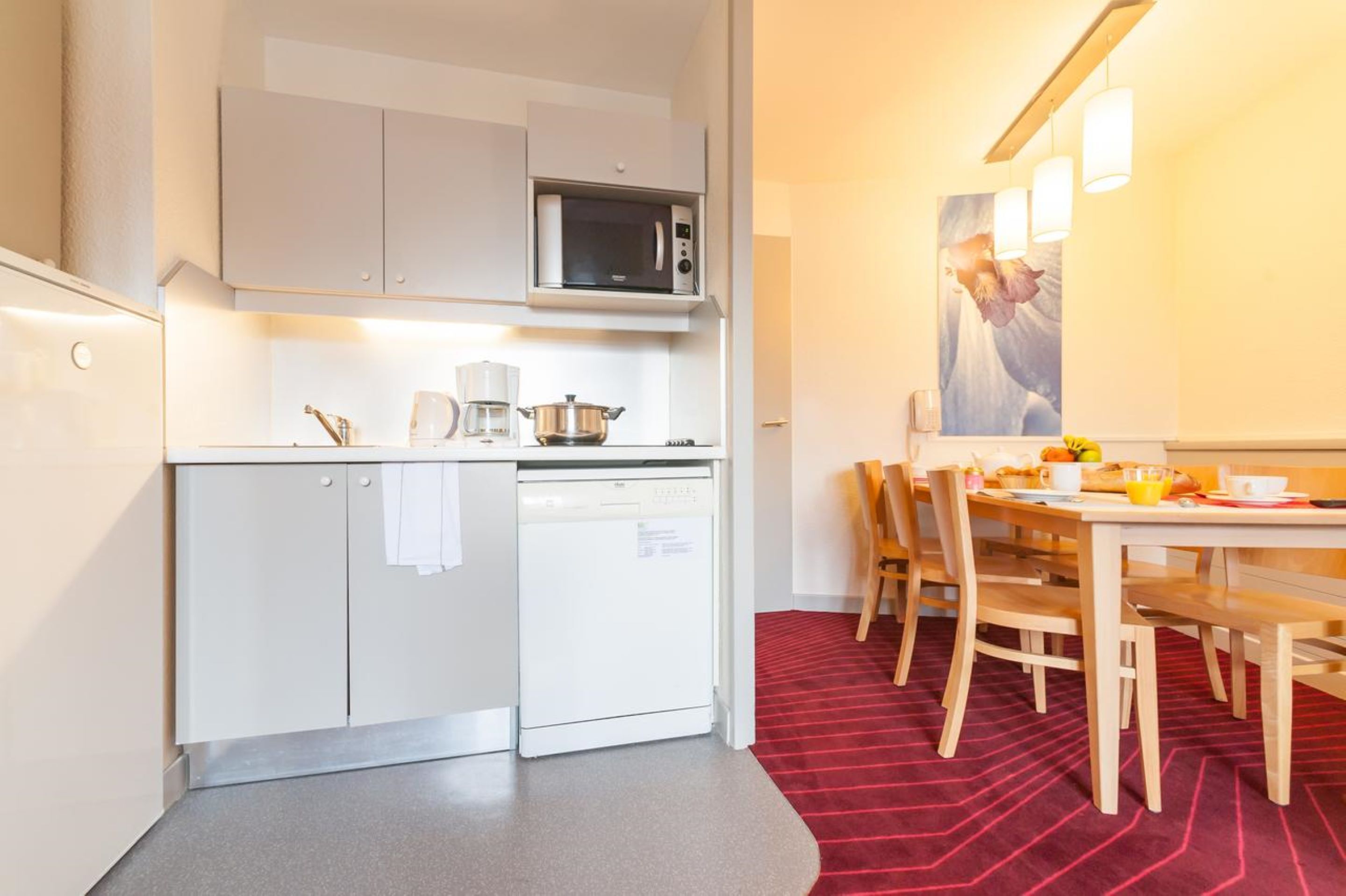 A compact kitchen with a microwave, dishwasher, and a dining area with a table and chairs.