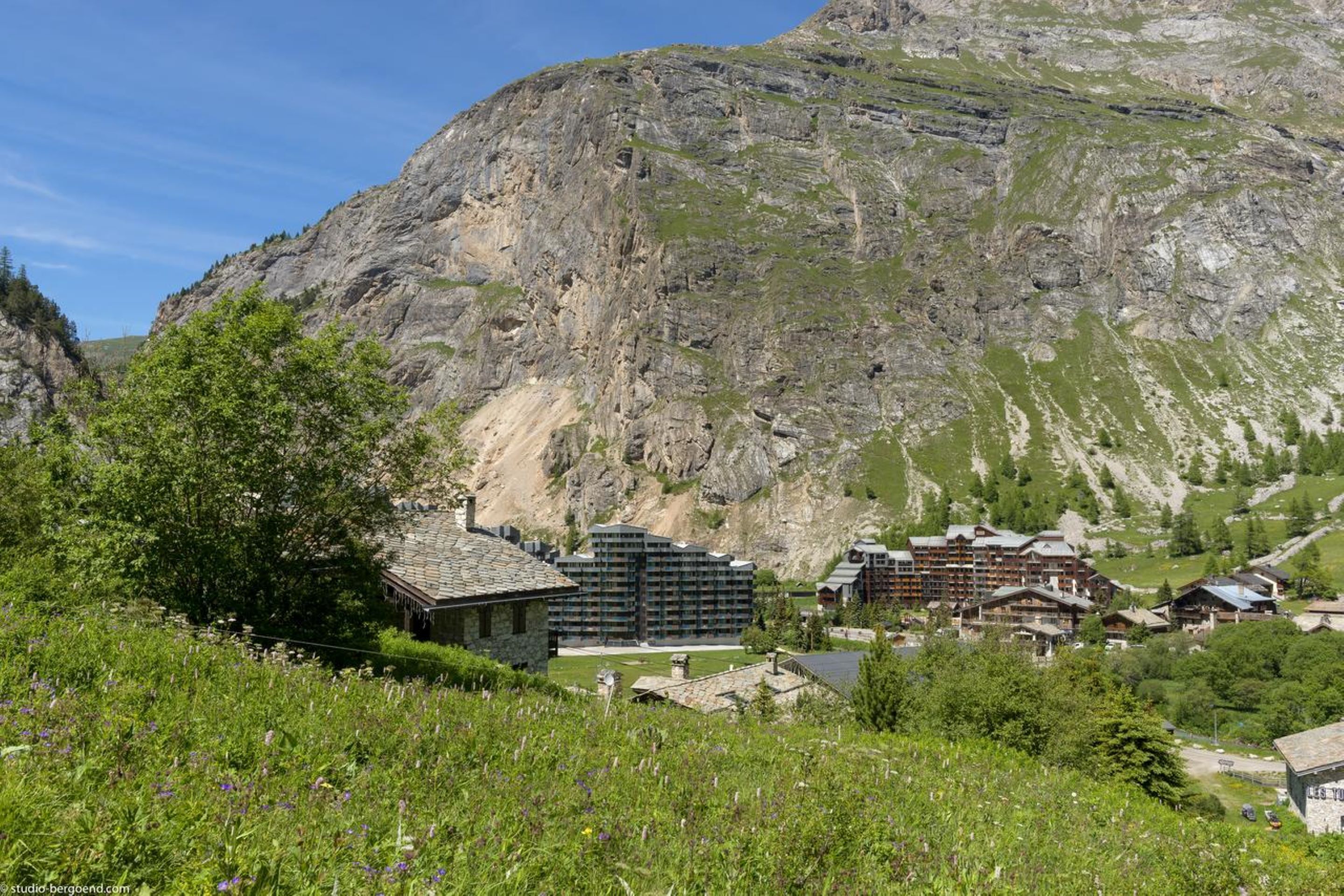 Eine Berglodge mit mehreren Gebäuden, umgeben von üppiger Vegetation und felsigem Gelände.