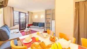 A hotel room with a dining area, a sofa, a TV, and a balcony with a view. - Résidence La Daille - Val-d'Isère (Val-d'Isere)