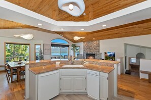 Une cuisine moderne avec un îlot central, un plafond en bois et une cheminée en pierre.